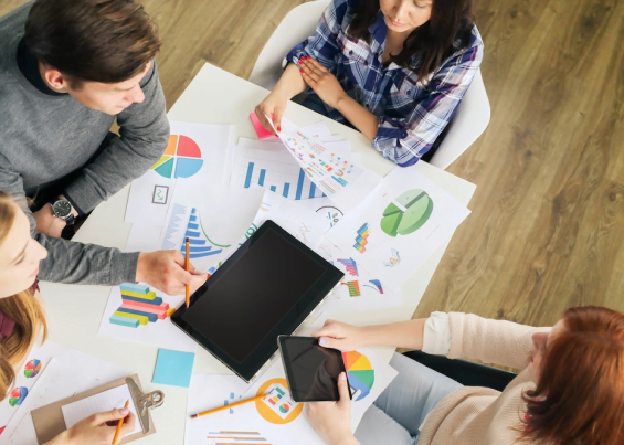 Team members discussing ideas using charts, pencils, and laptop